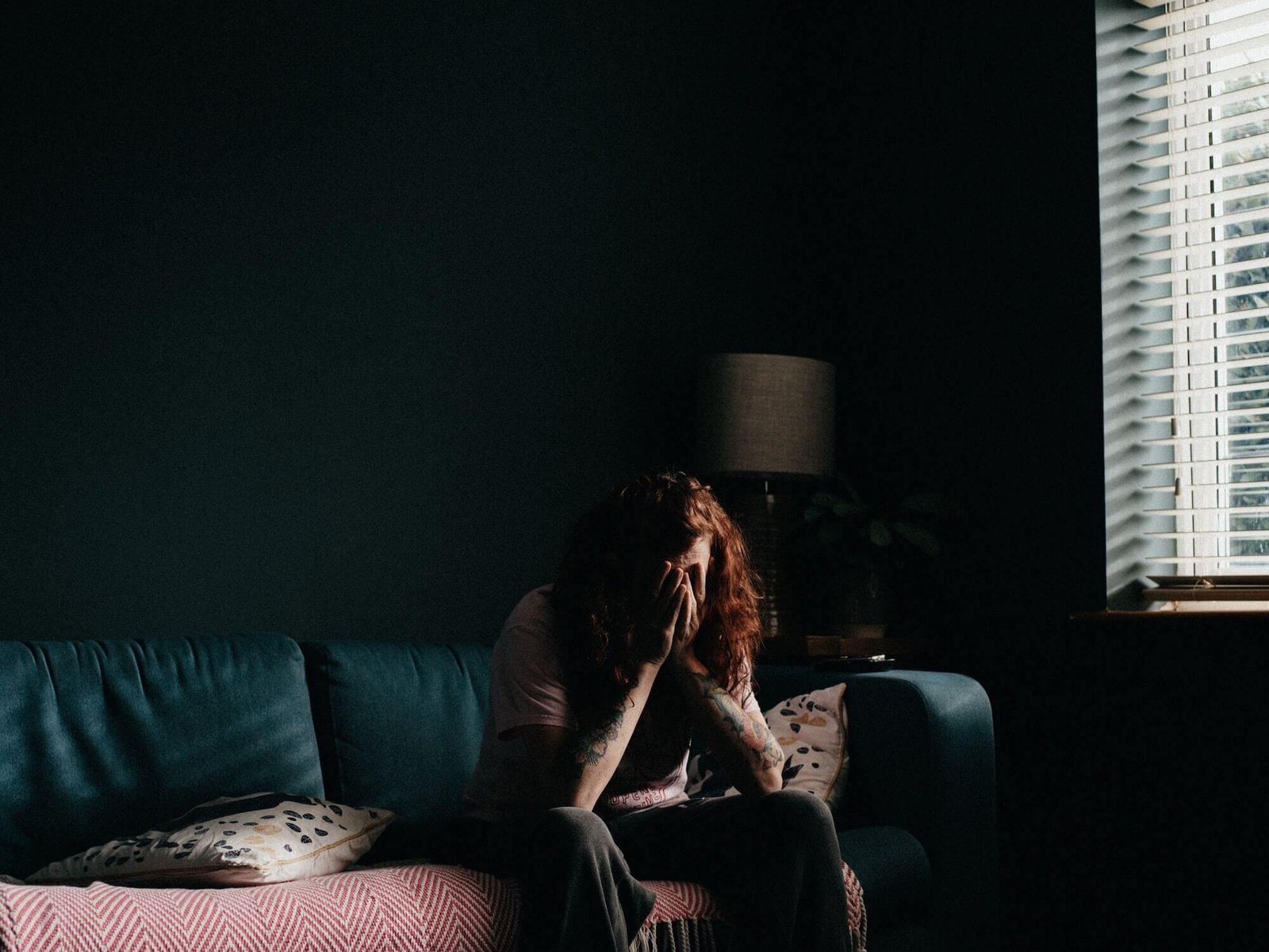Person sitting on a couch overwhelmed with head in hands