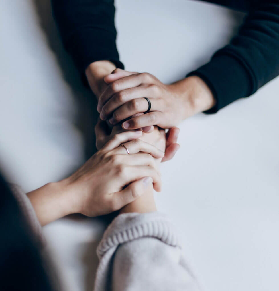 Hands being held across a table showing support of a client who may have PTSD.