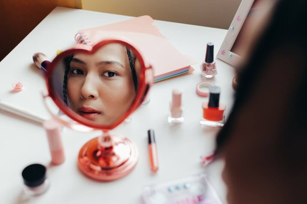 Person looking at their reflection in a heart-shaped hand mirror