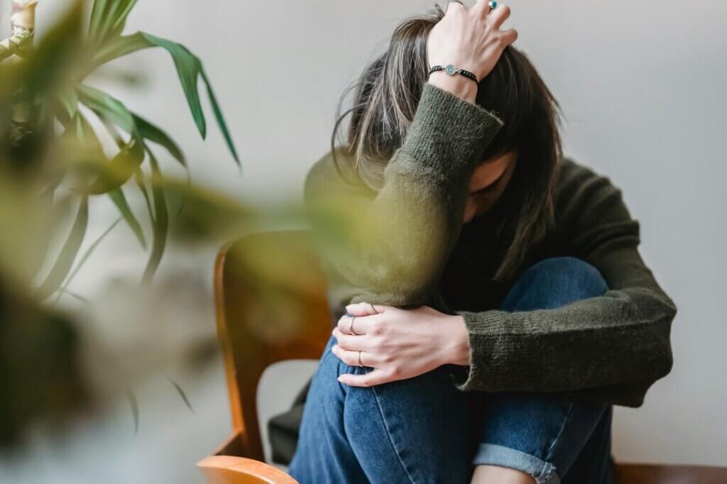 Woman sitting, head in hands, showing signs of adult anxiety or depression.