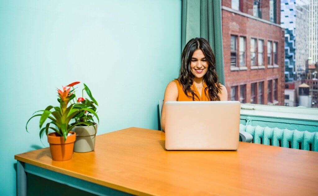 Woman working on laptop, plants on desk. Finding mental health support. EMDR in San Diego