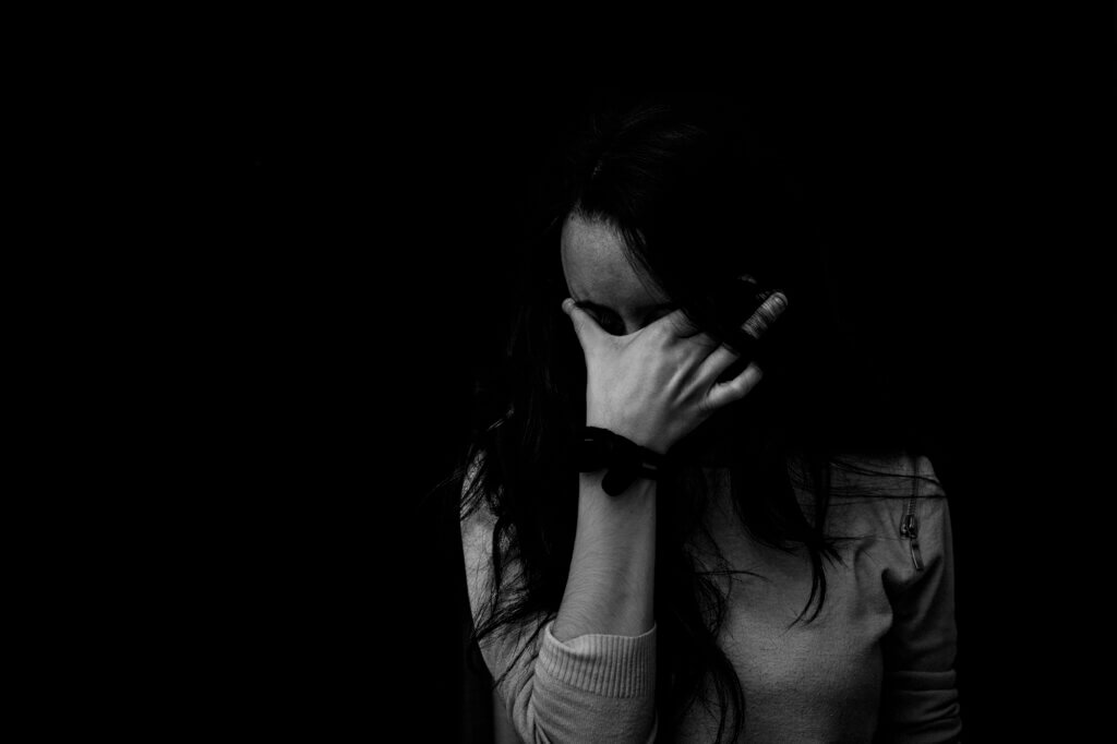 Woman with hand over face, showing sadness. Overcoming neglect.