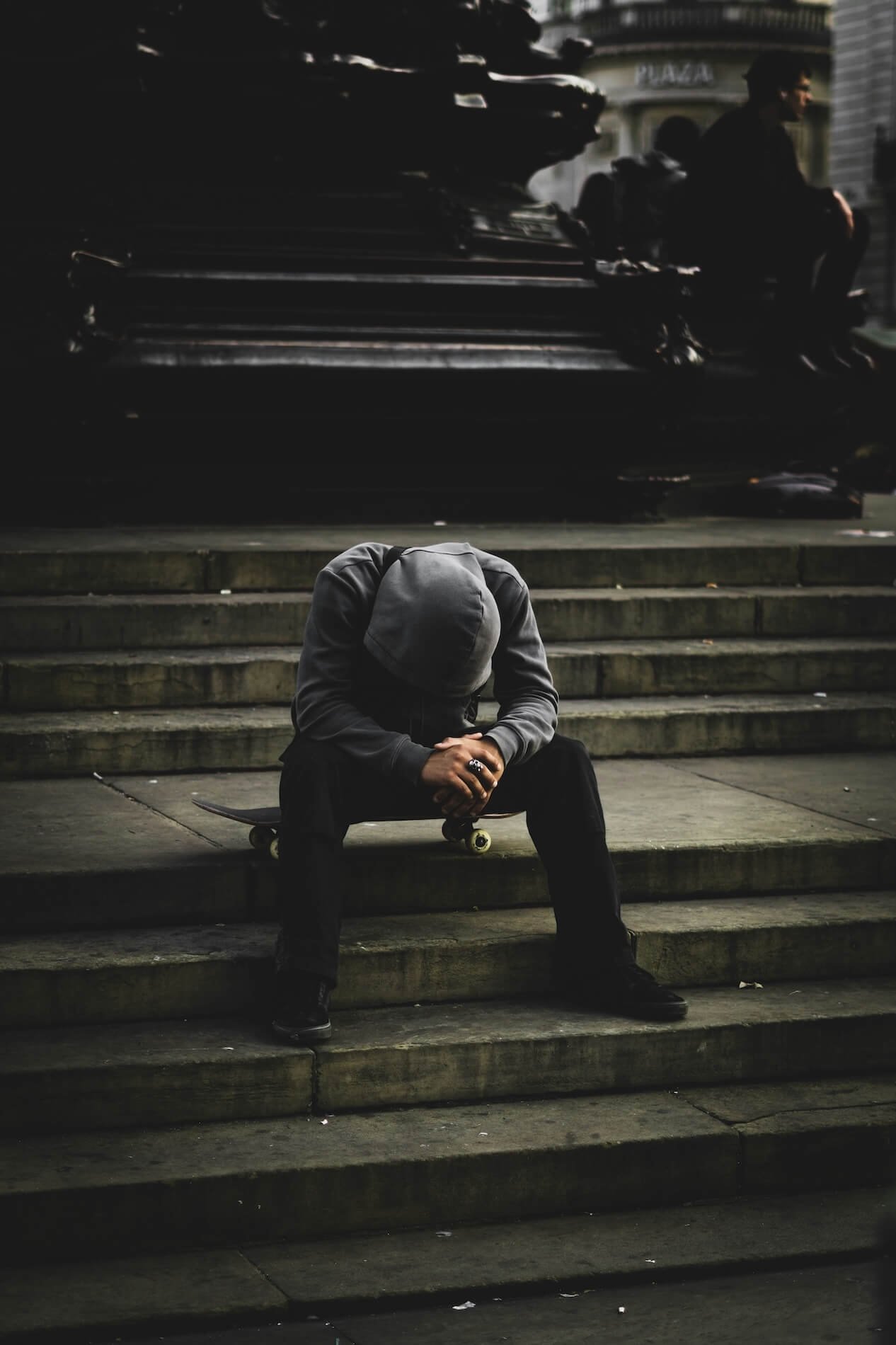 Person sitting alone on steps, head down, feeling isolated after trauma