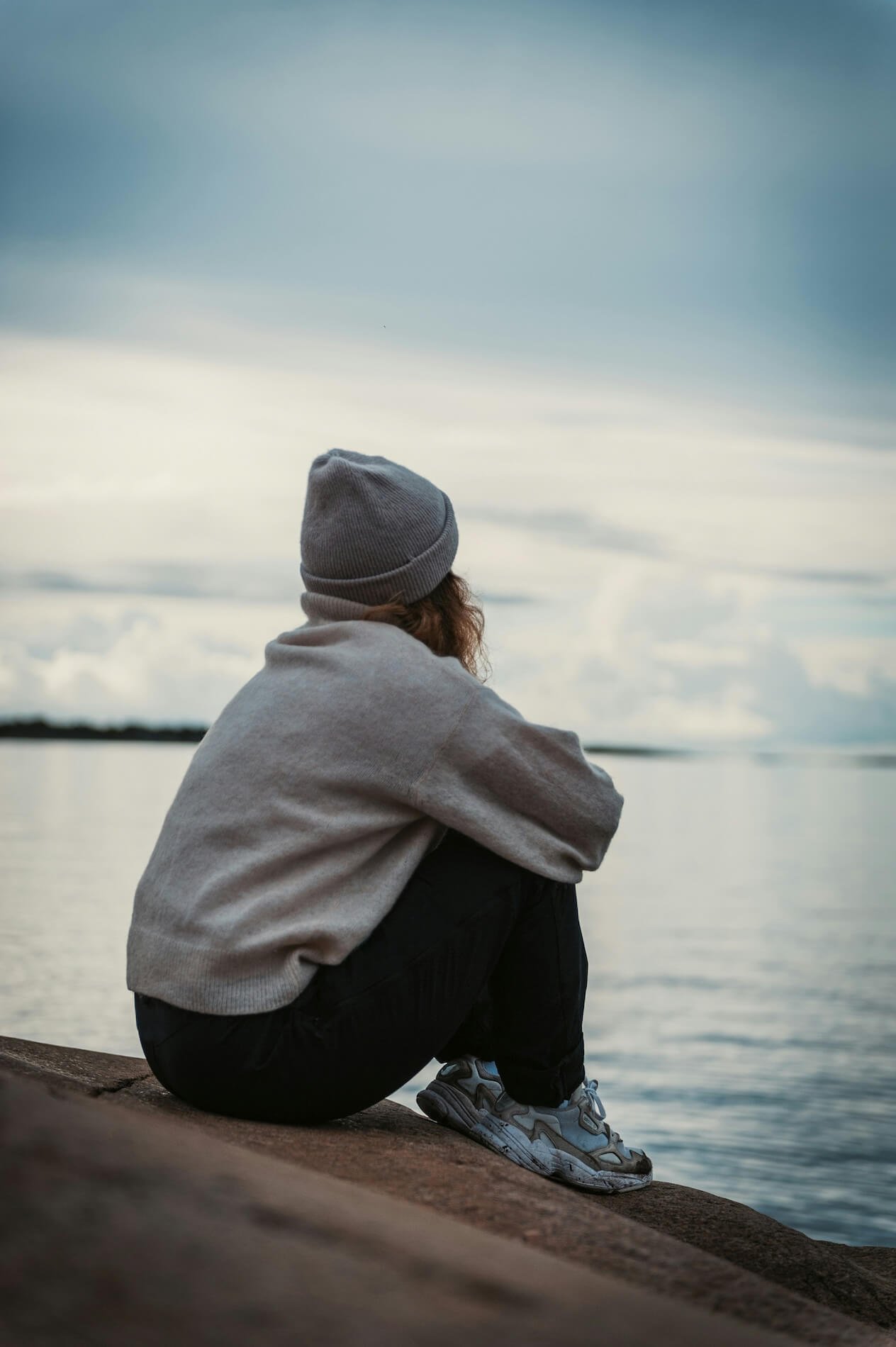 Person sitting quietly looking out at open water, a sense of calm and openness