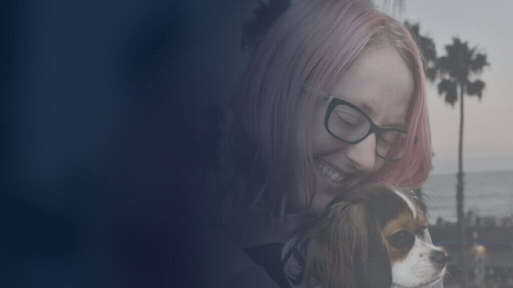 Shay DuBois, trauma therapist in San Diego, smiling and hugging her dog Luna